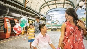 a mother and child walking by the boarding platform of cable cars, with father and son behind