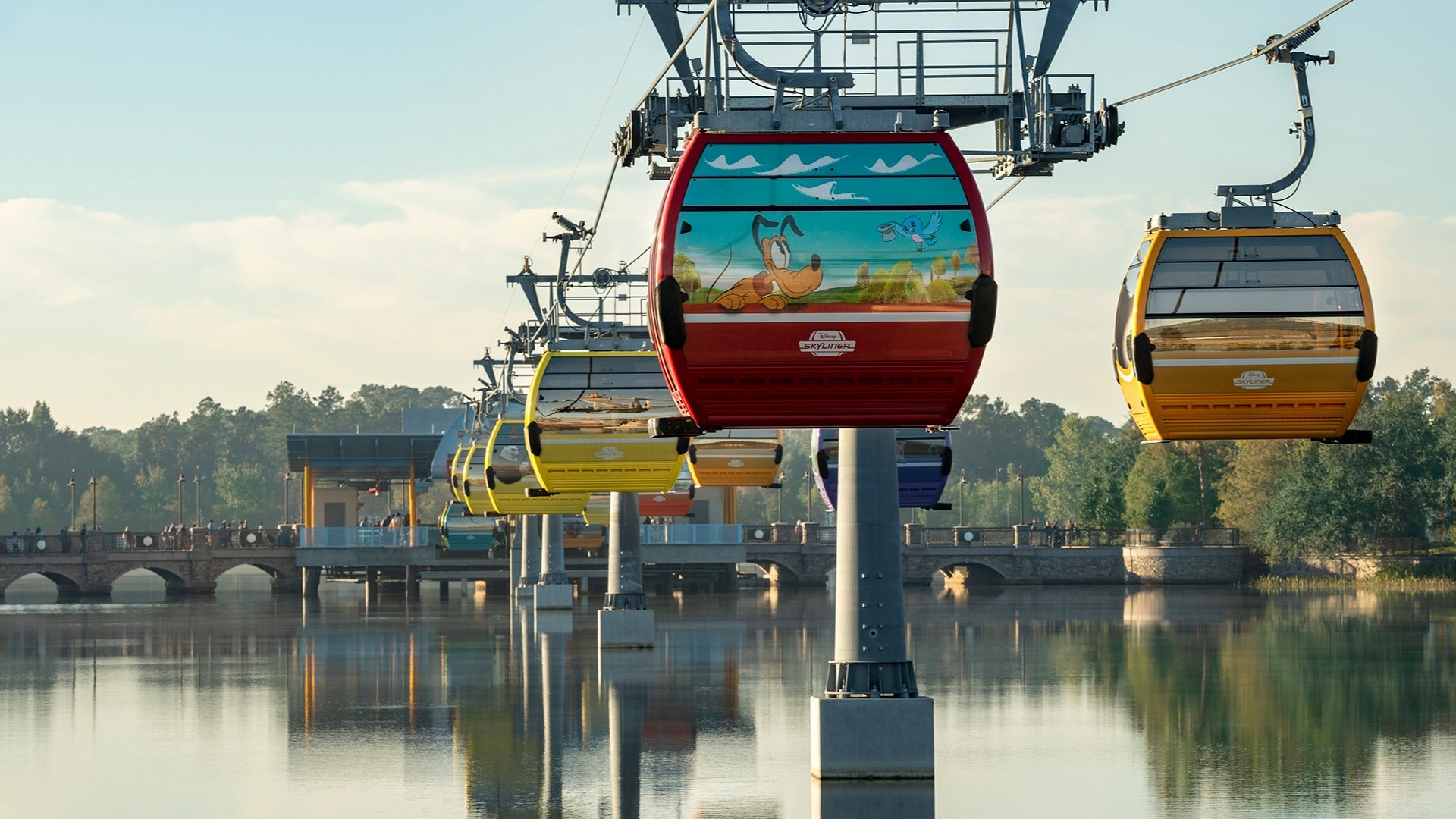 cable cars in various colors passing by a lake