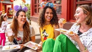 a group of friends wearing disney merch eating a variety of food