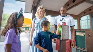 a kid using a lightning lane pass at a ride in disneyland with his family
