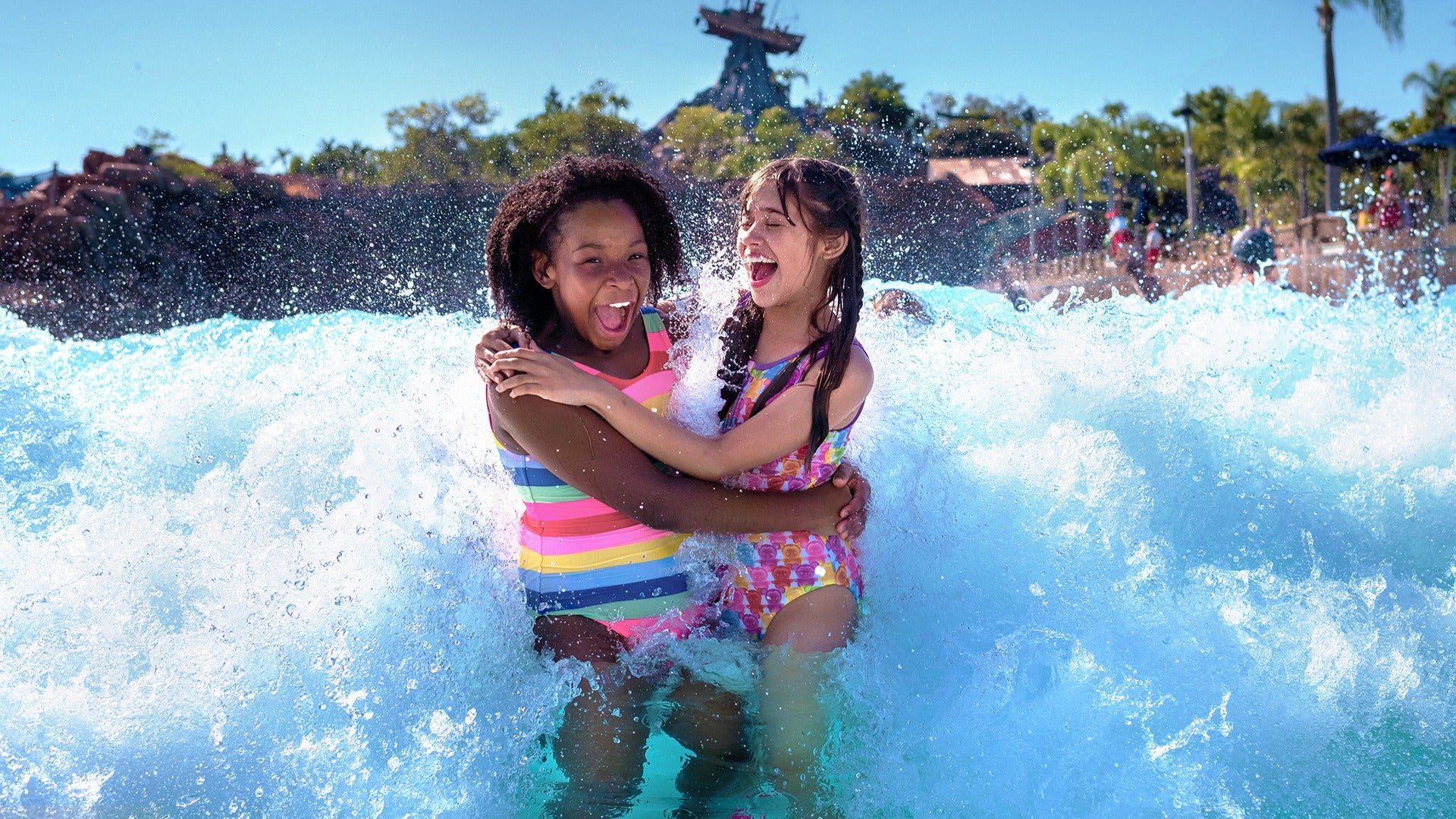 a woman and a child in a wave pool happily splashing around
