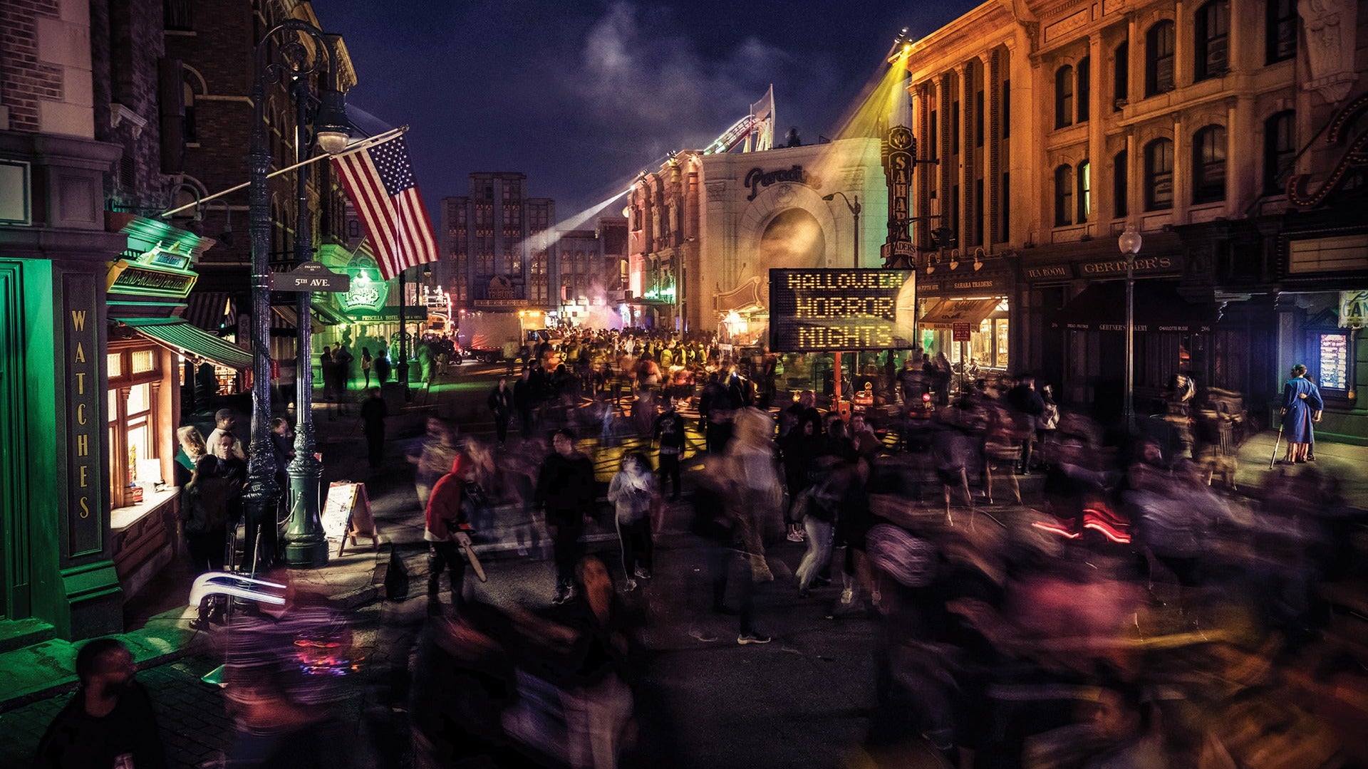 A packed Halloween Horror Nights scare zone at Universal Studios Hollywood with a marquee sign lit up at night