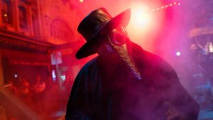 A plague doctor scareactor surrounded by red and pink fog at Halloween Horror Nights Hollywood