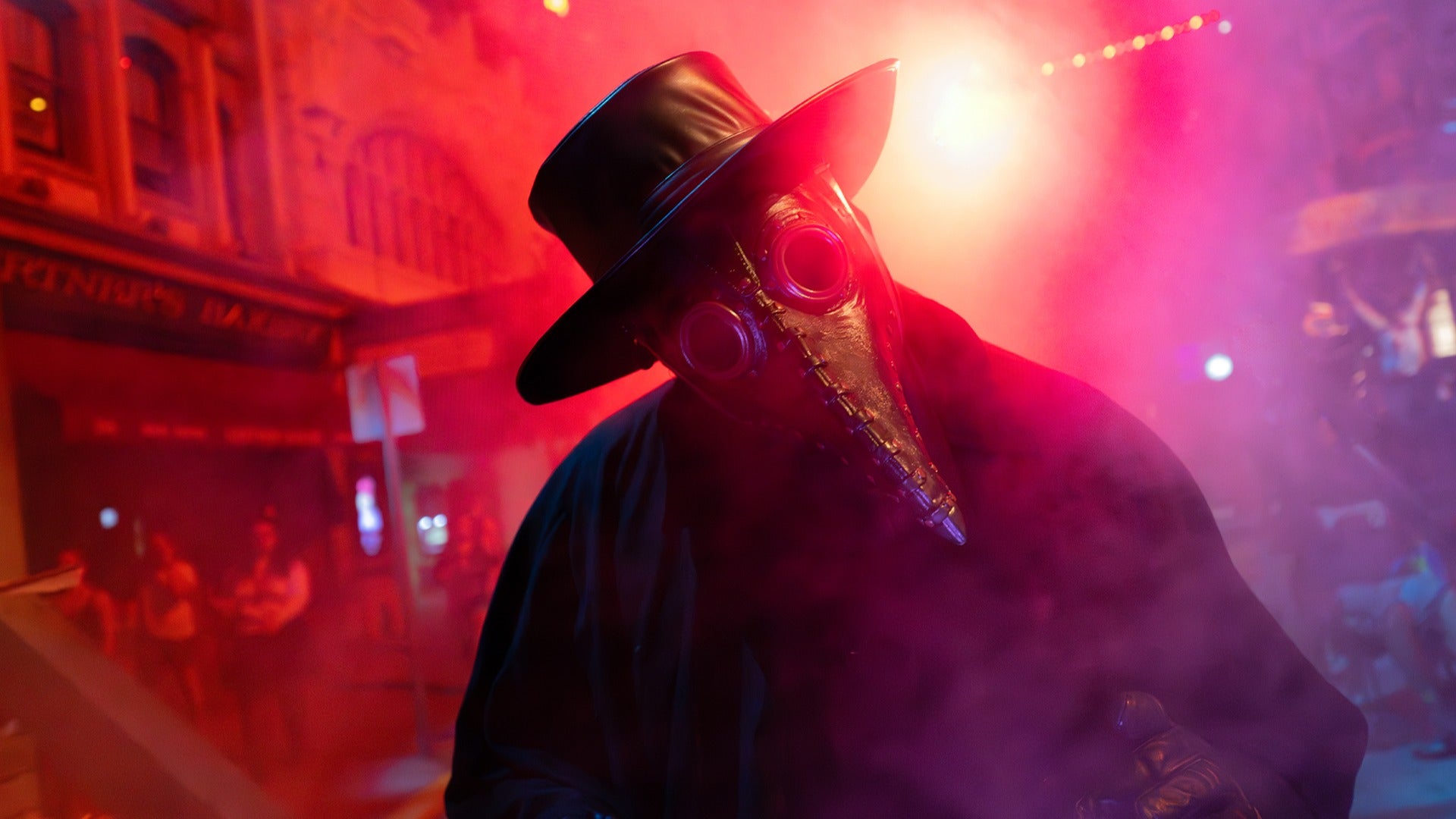 A plague doctor scareactor surrounded by red and pink fog at Halloween Horror Nights Hollywood