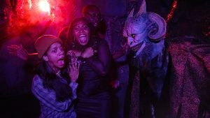 Guests reacting with fear to a creature scareactor inside a Halloween Horror Nights haunted house at Universal Studios