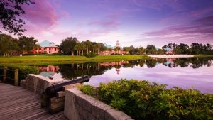 Wide shot of Disney’s Caribbean Beach Resort lake and buildings in the background at sunset