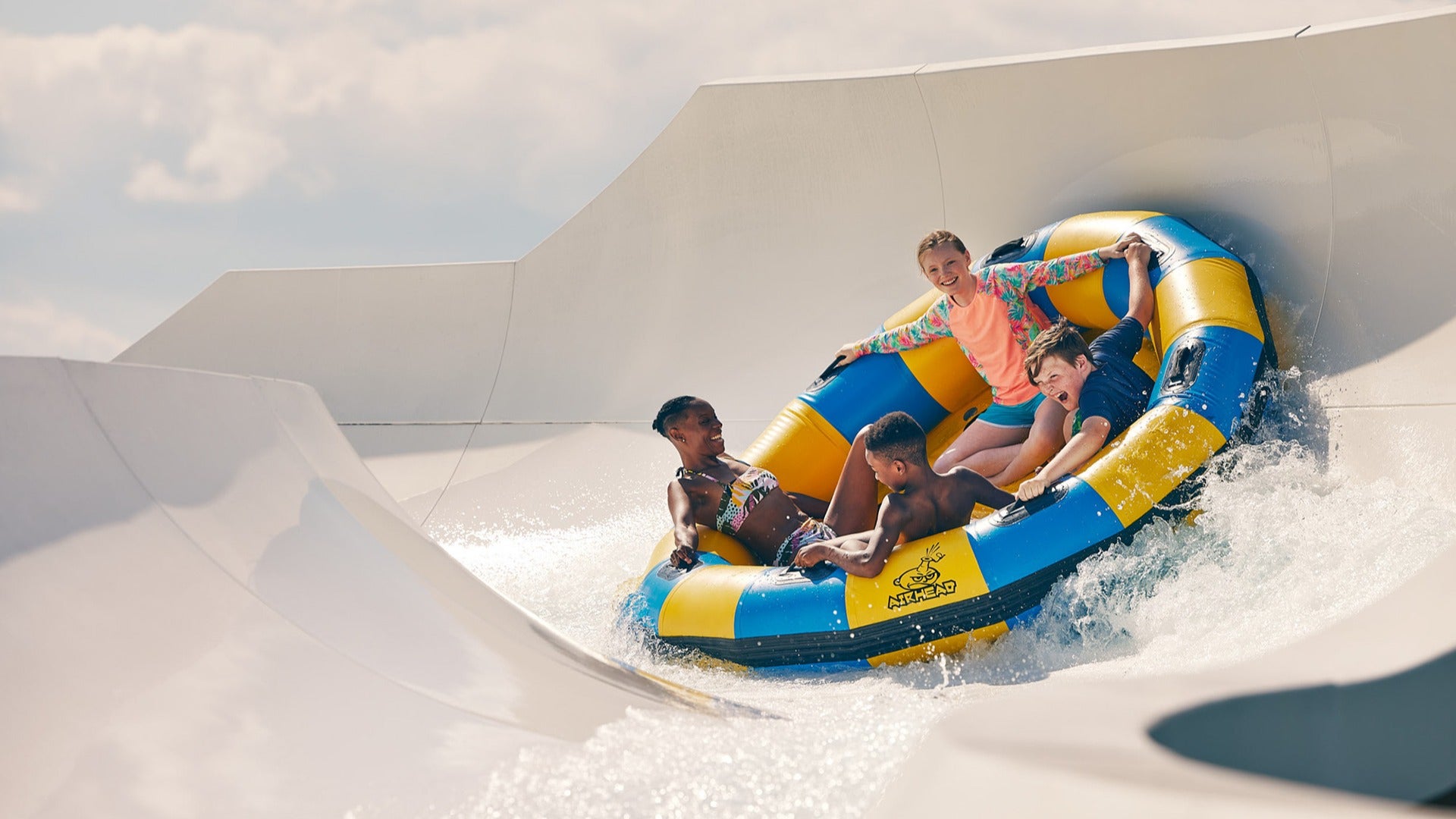 children and a woman in a floatie on a water slide