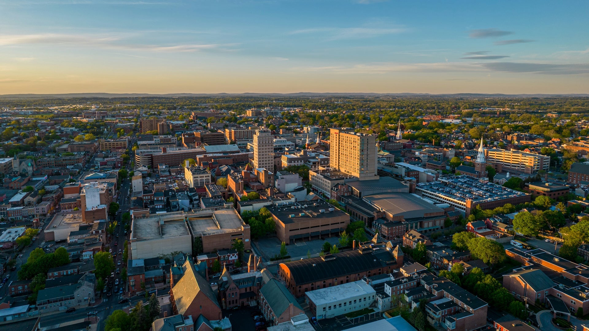 Aerial view of a city with a downtown and green trees under a blue sky