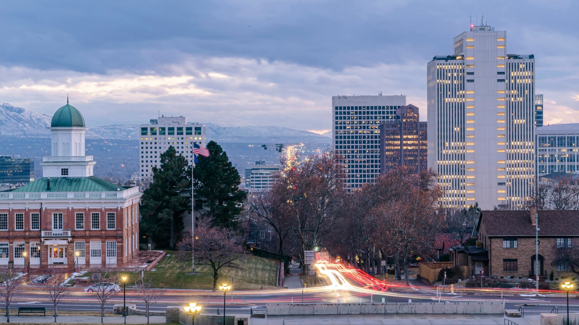 Downtown buildings at dusk with snow capped mountains in the background