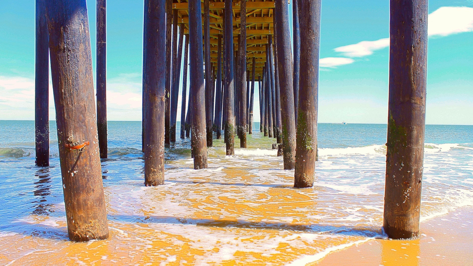 Looking out under a pier at the beach