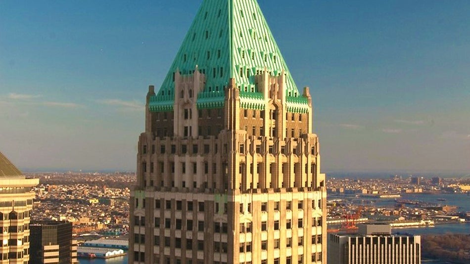 aerial shot of top of 40 Wall Street Building with view of New York City in background during a sunny day in New York City, New York, USA