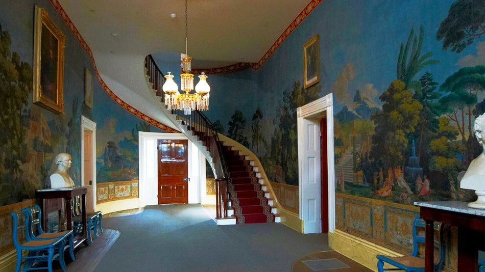 interior of Andrew Jackson's Hermitage featuring colorful painted walls, busts, a chandellier, stairs in Nashville, Tennessee, USA
