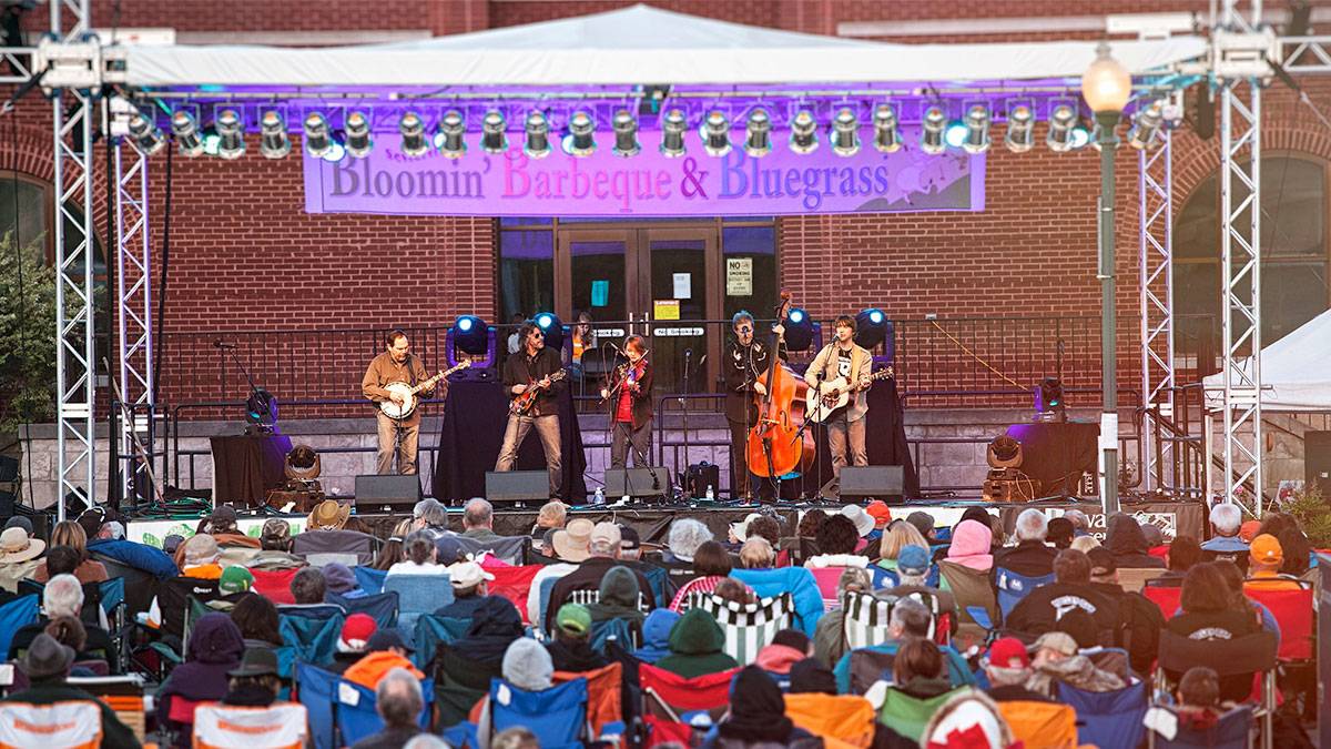performers on stage with banner and crowd on chairs watching at Bloomin' BBQ and Bluegrass Festival - Pigeon Forge, Tennessee, USA