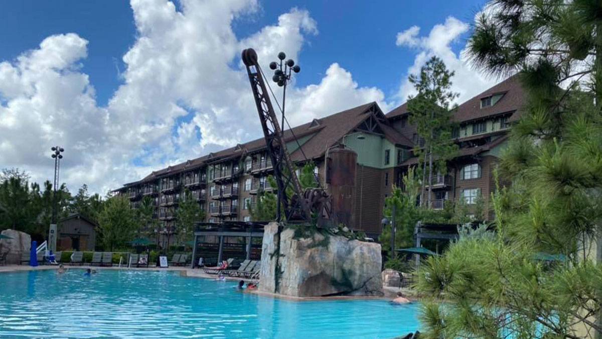 large blue pool with hotel in background and trees in area during daytime with blue sky and clouds at Boulder Ridge Cove Pool in Disney Wilderness Lodge, Florida, USA