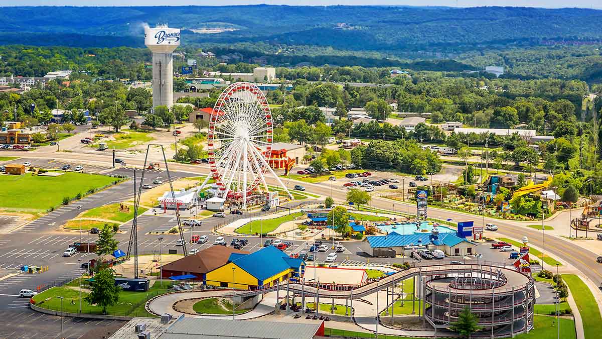aerial of Branson Entertainment District with various rides and attractions for kids with trees and mountains in the distance during the day in Branson, Missouri, USA
