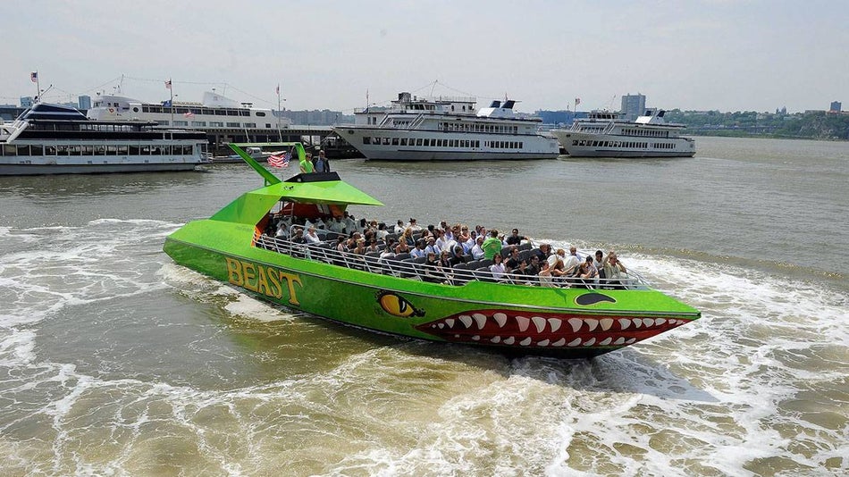people aboard bright green boat called The Beast by Circle Line Cruise on water with boats in the background in New York City, New York, USA