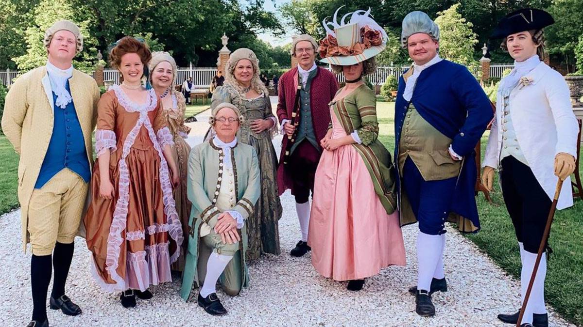 people dressed in period clothing posing for photo in garden on a sunny day at Colonial Fashion Days Colonial Williamsburg in Williamsburg, Virginia, USA