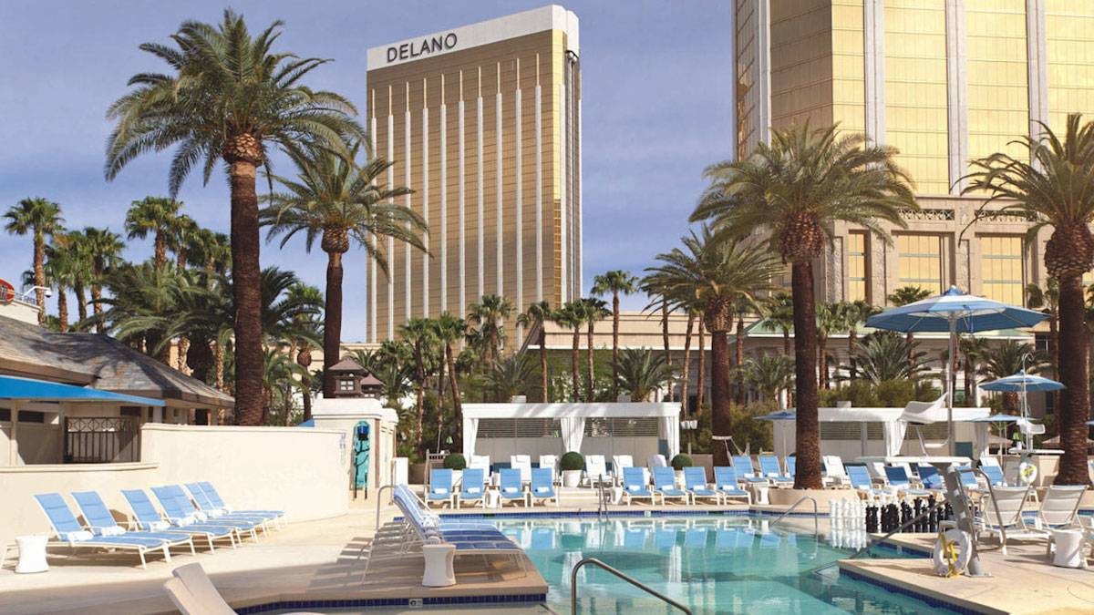 pool with lounge chairs, umbrellas, and palm trees and exterior of Delano Hotel at Las Vegas, Nevada, USA