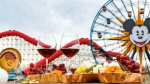 glasses of wine and a board with cheese and fruits with the Disneyland ferris wheel and rollercoaster in the background for the Food and Wine Festival at Disneyland, Anaheim, California, USA