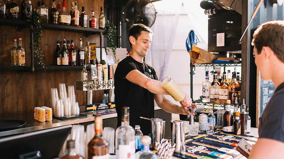bartender pouring drink behind bar for customer at Easy Tiger in Austin, Texas, USA