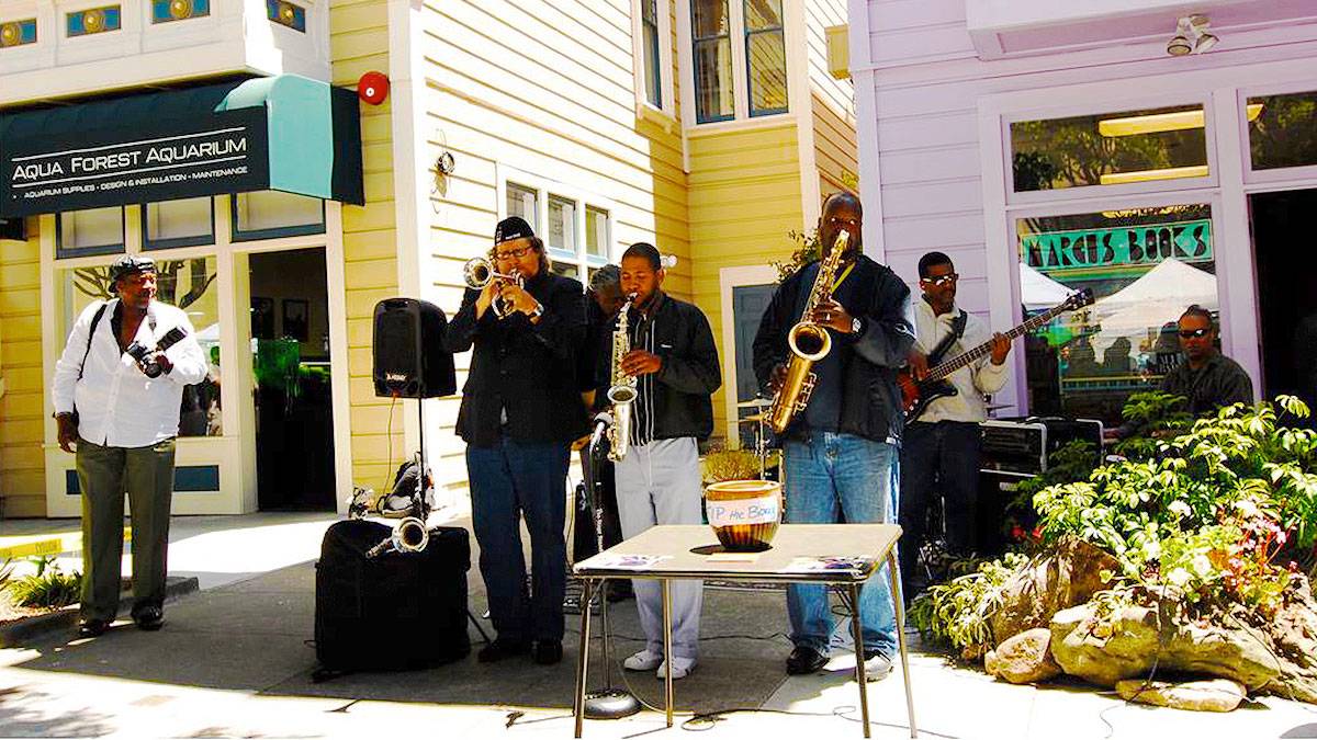musicians performing on street with man with camera on side at Filmore Jazz Festival in San Francisco, California, USA