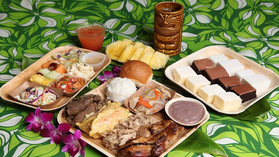 plates of food and drink served at Germaine's Luau over green printed table cloth in Oahu, Hawaii, USA