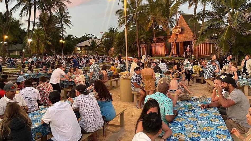 people seated on outdoor tables in front of stage at Germaine's Luau in Oahu, Hawaii, USA