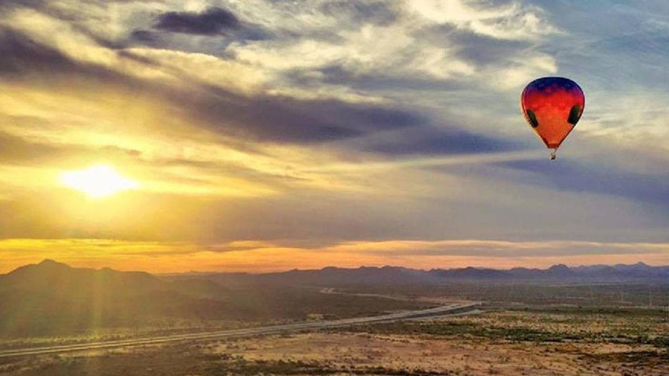 aerial view of hot air balloon over landscape with mountains and sun shining through clouds in Phoenix, Arizona, USA