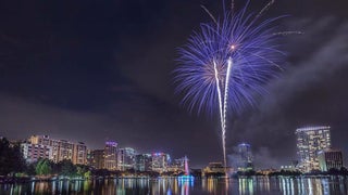 fireworks over cityscape of Orlando at night with view of body of water for Indepence Day in Orlando, Florida, USA