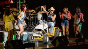 Kenny Chesney impersonator performing onstage on top of tractor with backup dancers at Legends of Country in Branson, Missouri, USA