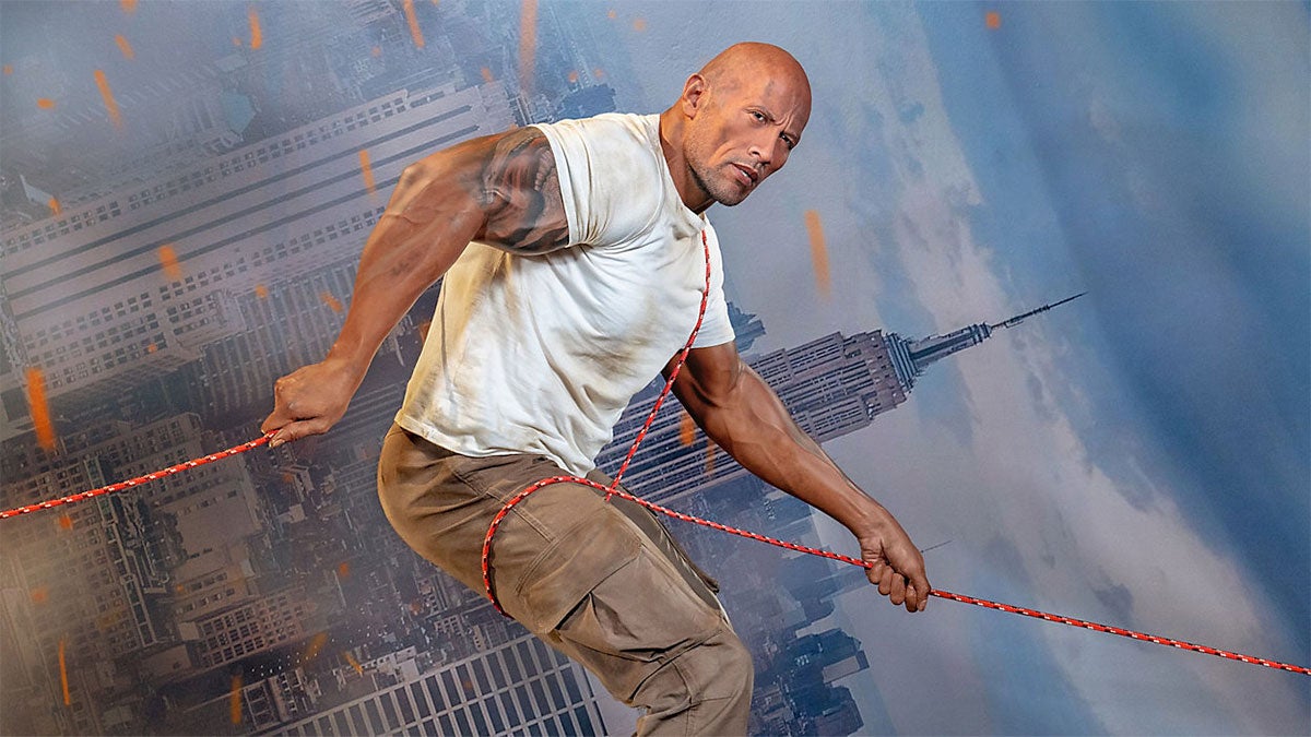 Wax Figure of Duane "The Rock" Johnson holding rope simulating climbing down building with backdrop of buildings behind figure in Madame Tussauds Orlando, Florida, USA