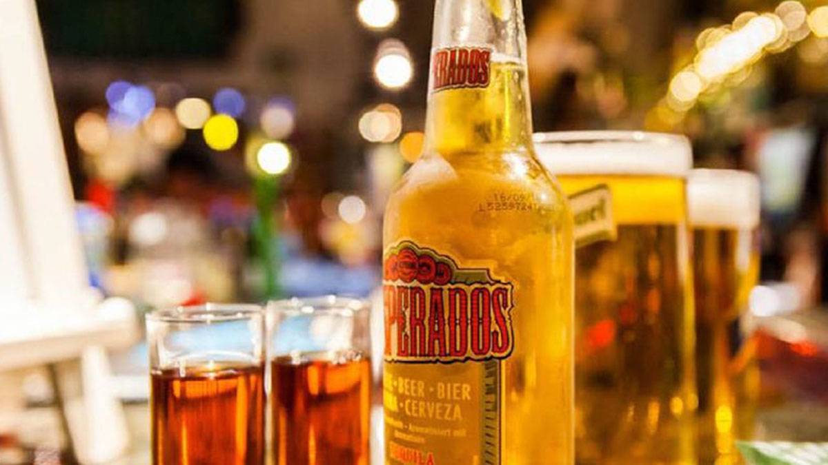 close up of beer bottle with glasses and beer pints in background