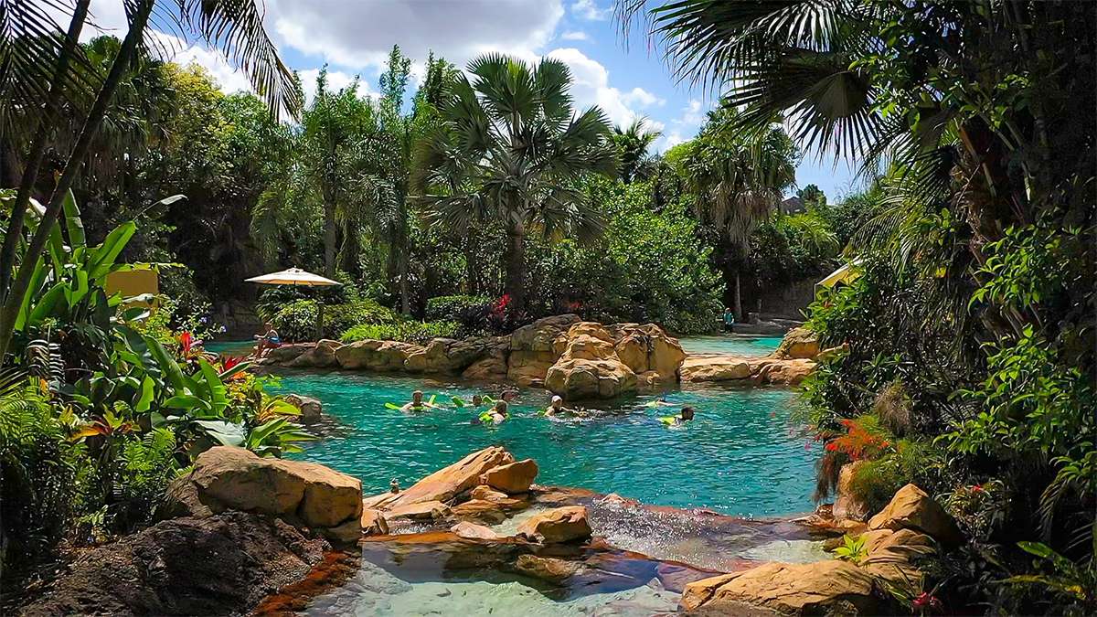 Wide shot of people swimming in the blue water of Wind-Away River on a Sunday at Discovery Cove in Orlando, Florida, USA