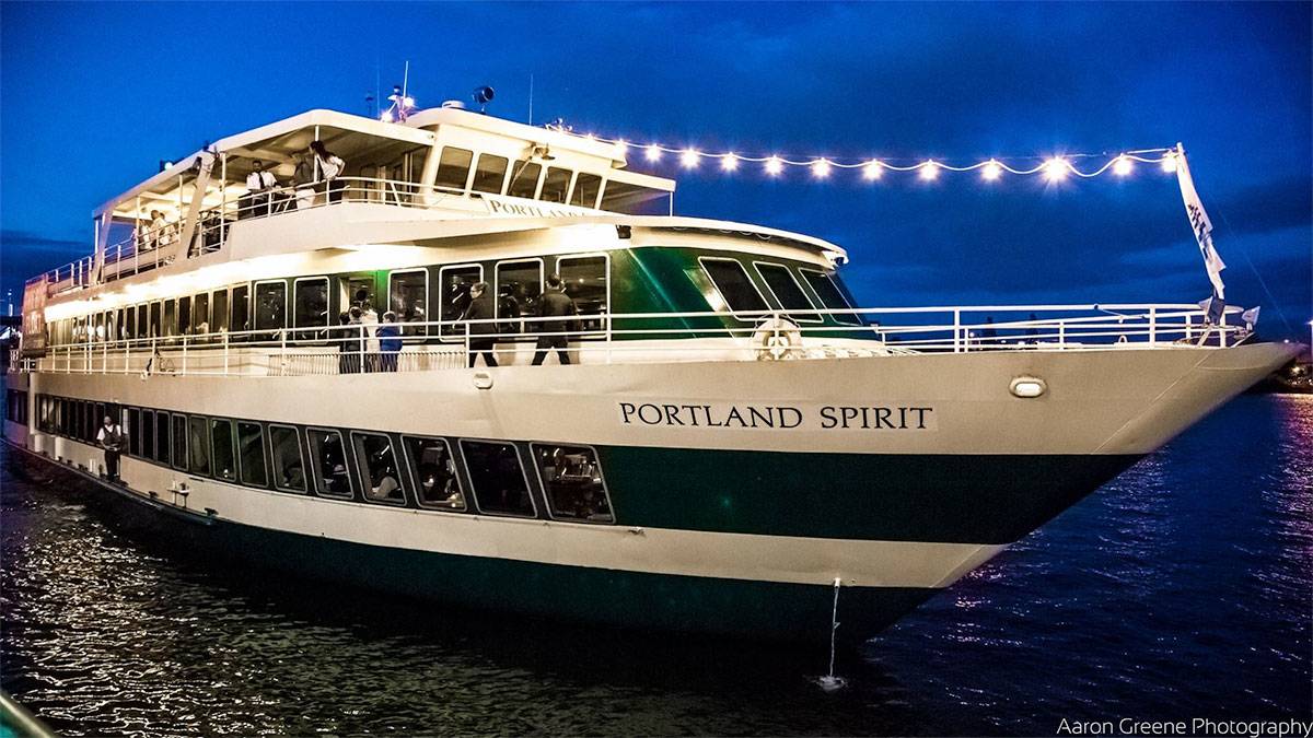 Portland Spirit Cruise on water at night with passengers and crew on board and lights lit up on deck in Oregon, USA