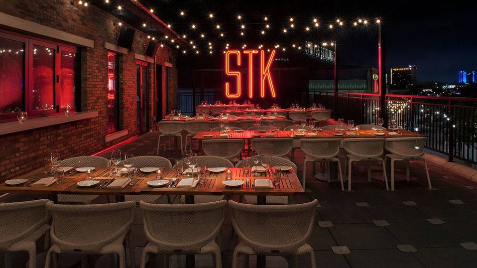 rooftop of STK Steakhouse restaurant with tables and chairs and large neon STK sign in Orlando, Florida, USA