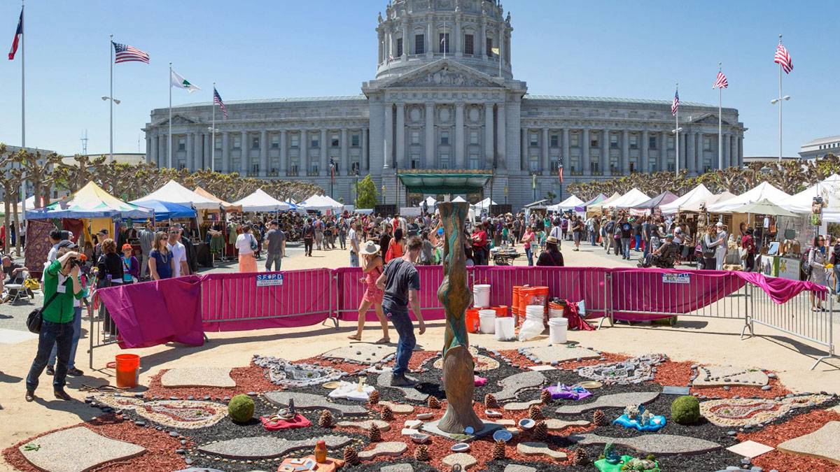 man working on installation and crowd walking around looking at booths at San Francisco Earth Day, San Francisco, California, USA