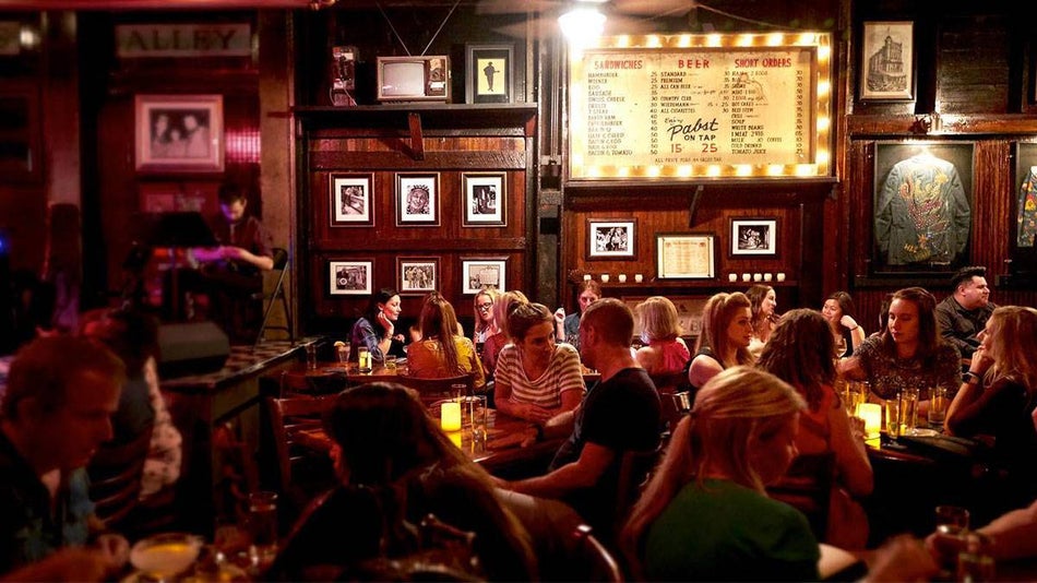 people dining at Skull's Rainbow Room Printers Alley with various picture frames and memorabilia on wall in Nashville, Tennessee, USA