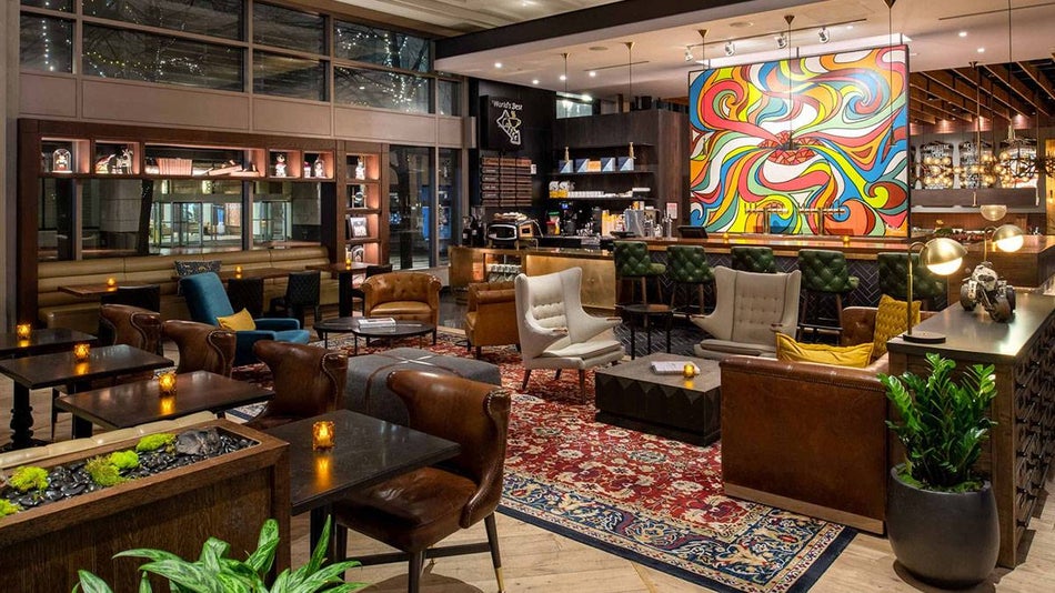 lounge area with chairs, tables, plants, persian rug, colorful artwork at The Duniway Portland in Portland, Oregon, USA