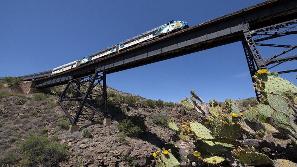 train on bride over desert with cactus plants in the foreground - Arizona, USA