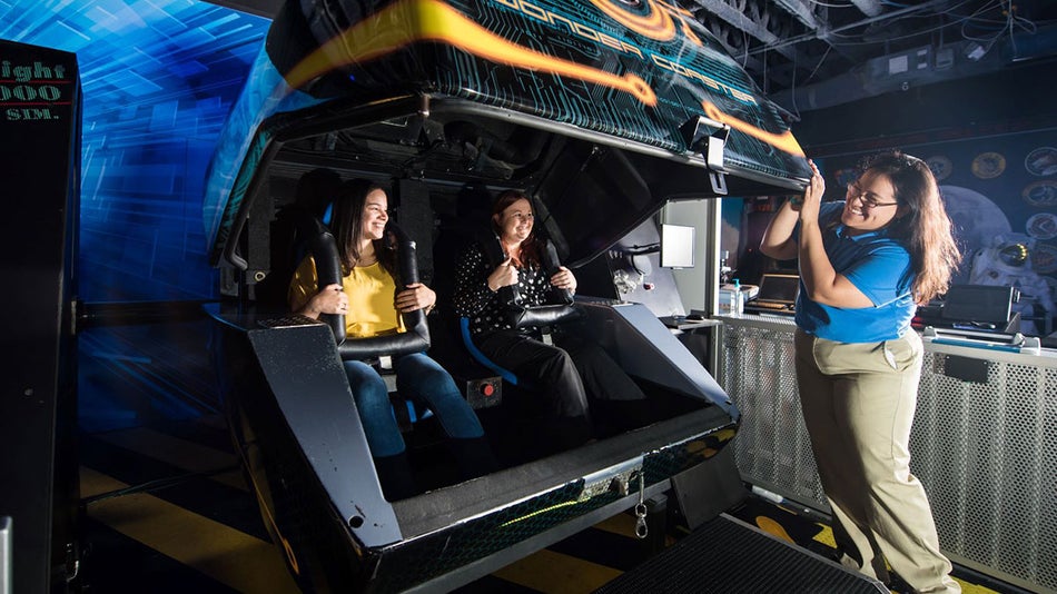 guests seated in the Wonder Coaster ride while being helped by staff at WonderWorks, Orlando, Florida, USA