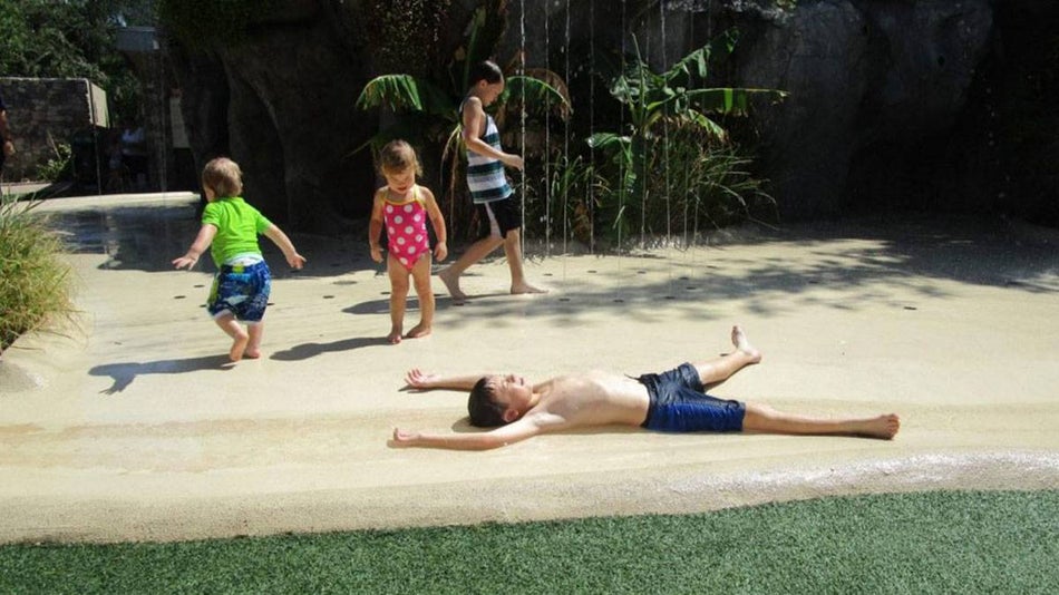 child sprawled on the shore with other children playing in the background at Yakulla Caverns in Phoenix Zoo, Phoenix, Arizona, USA