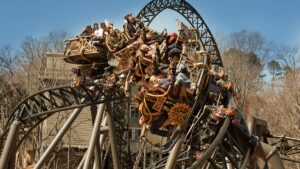 Close up of the Time Traveler Coaster full of people going sideways on a sunny day at Silver Dollar City in Branson, Missouri, USA