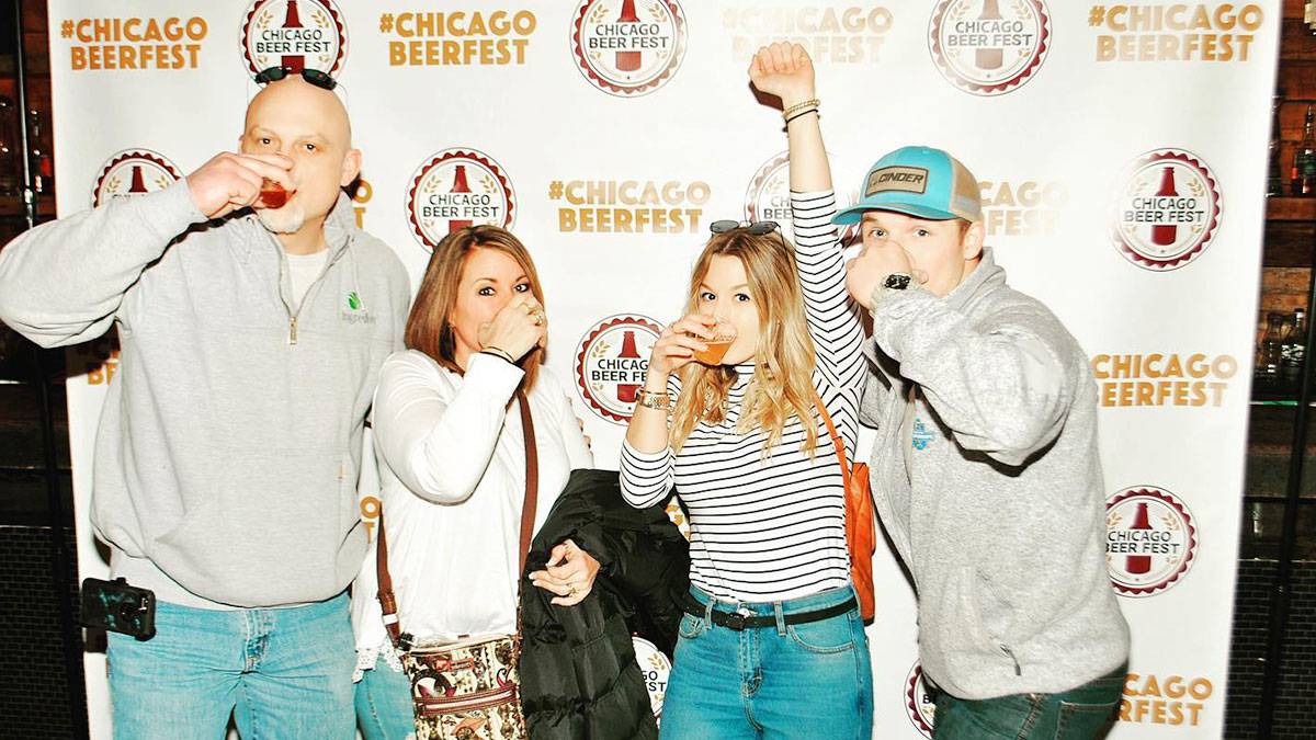 friends holding drinks posing for photo in photobooth of Chicago Beer Fest in Chicago, Illinois, USA