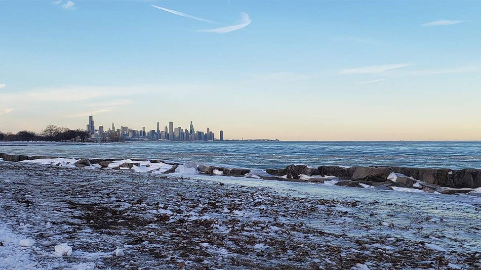 View of the water on a winter day with snow on the rock and the city in the background at Promontory Point in Chicago, Illinois, USA