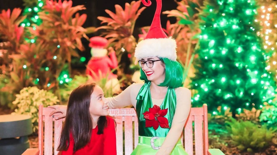 Close up of a family enjoying hot chocolates in Santa hats and light necklaces with Christmas trees in the background at ZooTampa in Tampa, Florida, USA