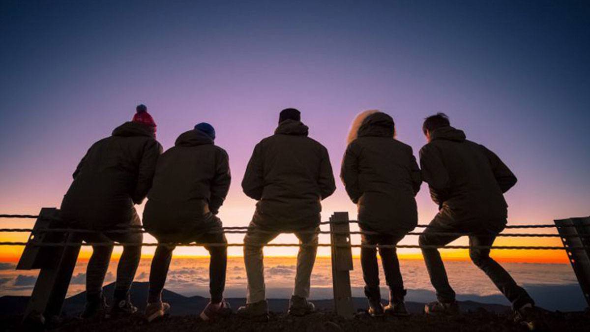 friends sitting together watching the sunrise during the Mauna Kea Sunrise Experience in Kailua Kona, Hawaii, USA