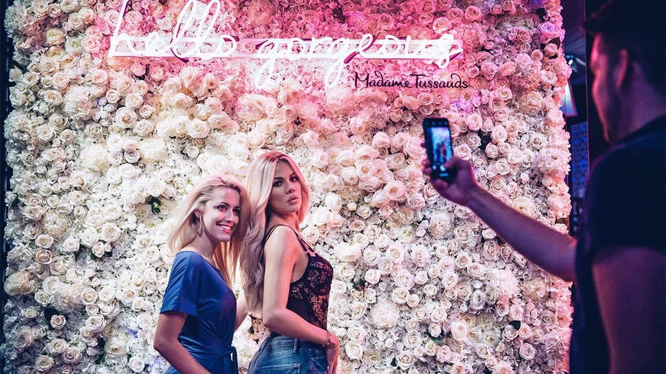 A young blonde women posing with the Khloe Kardashian wax figure and a man taking her photo at Madame Tussauds in Las Vegas, Nevada, USA