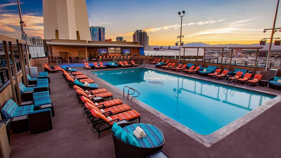Wide shot of the Elation Pool Café & Bar with orange and blue lounge chairs and the sunsetting in the background in Las Vegas, Nevada, USA