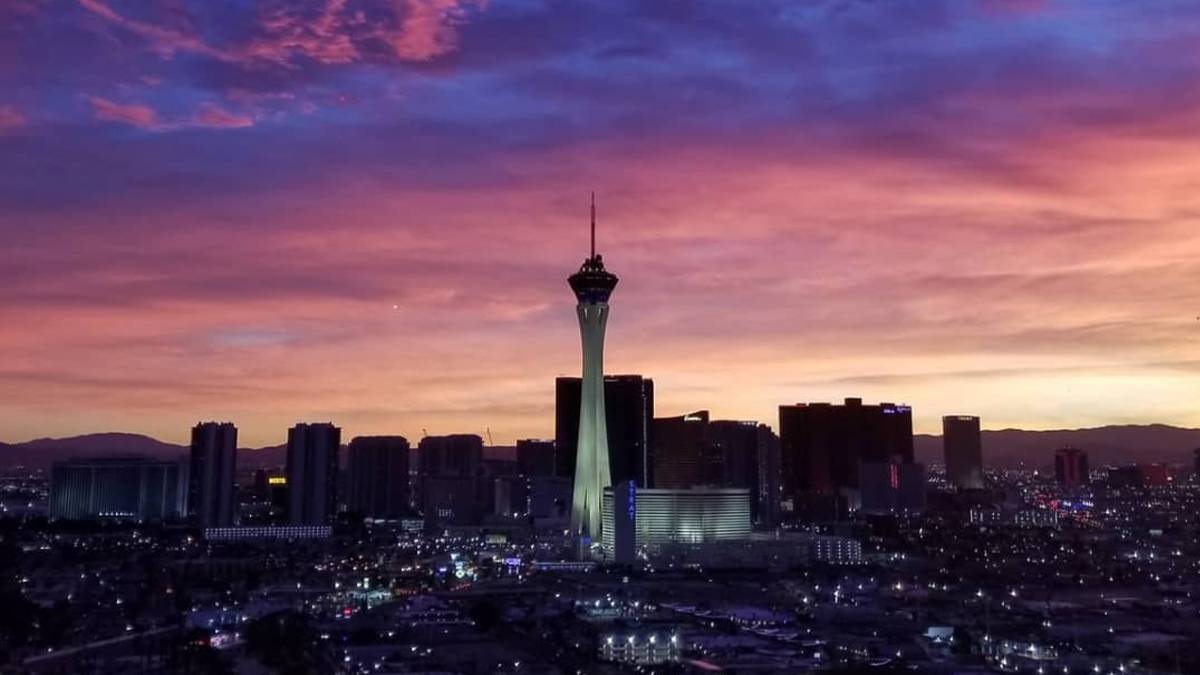 View of the STRAT Tower and the city skyline with a pink and purple sunset in Las Vegas, Nevada, USA