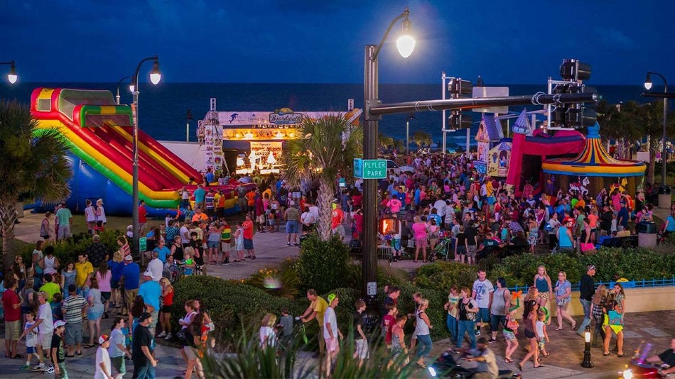 Wide shot of Ocean Boulevard’s Hot Summer Nights at dusk filled with people and bounce houses and carnival games in Myrtle Beach, South Carolina, USA